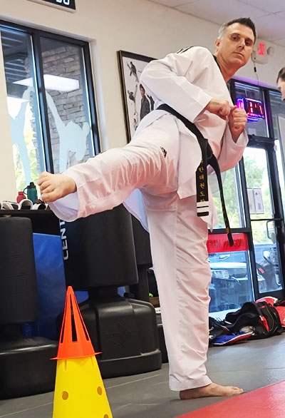 a black belt is practicing a kick at teen and adults class