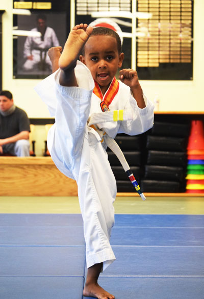 a kid is doing front kick in Kids Tiger Class